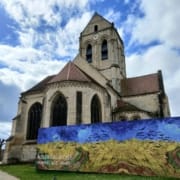Die Kirche Notre-Dame-de-l'Assomption in Auvers-sur-Oise mit einer Reproduktion von Van Goghs Weizenfeld mit Krähen