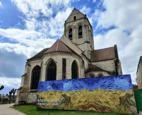 Die Kirche Notre-Dame-de-l'Assomption in Auvers-sur-Oise mit einer Reproduktion von Van Goghs Weizenfeld mit Krähen