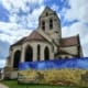 Die Kirche Notre-Dame-de-l'Assomption in Auvers-sur-Oise mit einer Reproduktion von Van Goghs Weizenfeld mit Krähen