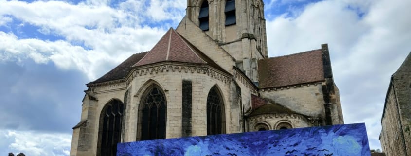 Die Kirche Notre-Dame-de-l'Assomption in Auvers-sur-Oise mit einer Reproduktion von Van Goghs Weizenfeld mit Krähen